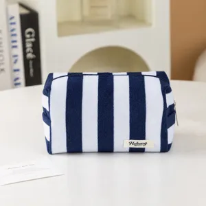 Vista dettagliata della borsa cosmetica in spugna a righe blu e bianche, morbida.
