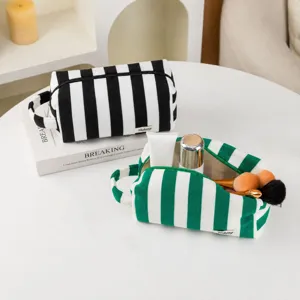 Detailed view of portable striped plush makeup bags in black-white and green-white designs.