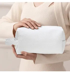 White waffle cosmetic bag detail showcasing soft fabric texture, portable handle and secure zipper.