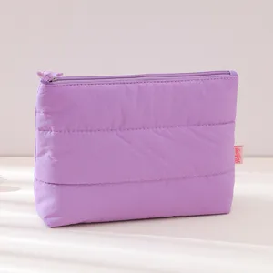 Purple quilted cosmetic pouch detail, soft puffy travel makeup bag texture display.