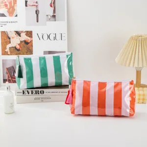 Close-up detail of colorful striped PVC cosmetic bag with elegant tassel and smooth zipper.