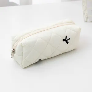 White quilted pencil case makeup bag with cute black bow embroidery, minimalist storage detail view.