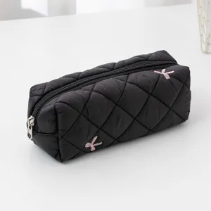 Black quilted pencil case detail, diamond lattice texture with sweet bow embroidery.