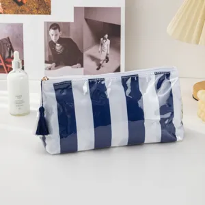Blue white striped PVC cosmetic bag detail, sleek tassel zipper pull, waterproof travel pouch.