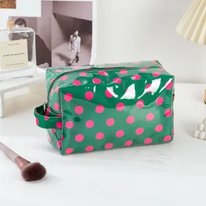 Green polka dot PVC cosmetic bag detail shot, waterproof travel zipper toiletry storage pouch.
