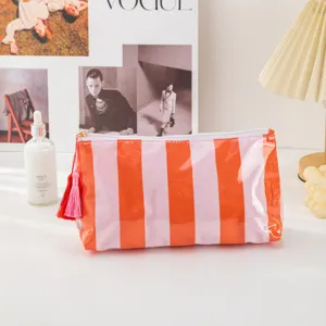 Close-up detail of the glossy striped cosmetic pouch with tassel and clean stitching.