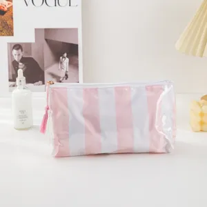 Pink and white striped PVC cosmetic bag detail shot, portable makeup storage pouch with tassel.