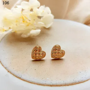 Primo piano di orecchini a lobo a cuore trapuntati placcati in oro 14K su piatto di ceramica.