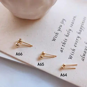Nahaufnahme von minimalistischen goldenen Kugel-Ohrringen, die feinen Metallglanz zeigen.