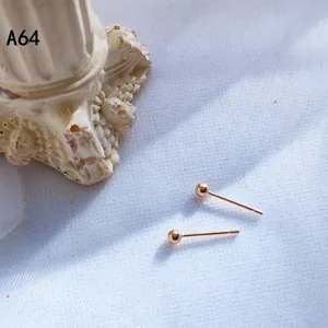 Detailansicht minimalistischer goldener Kugel-Ohrstecker vor weißem Hintergrund mit Säule.