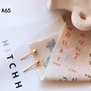 Nahaufnahme minimalistischer Goldkugel-Ohrstecker, zartes kleines geometrisches Design.