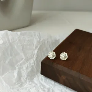 Nahaufnahme Detail minimalistischer silberner Blumen Ohrstecker auf Holzblock Display