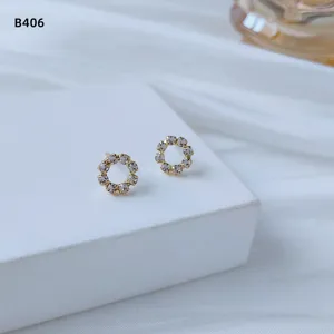 Nahaufnahme von minimalistischen kleinen runden Ohrringen mit funkelnden Zirkoniasteinen besetzt.