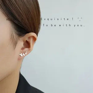 Nahaufnahme Detail silberner Zweig Blatt Ohrstecker am Ohr, minimalistischer Alltagsschmuck.