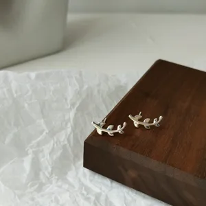 Nahaufnahme von Mini-Ohrringen mit silbernem Blätter-Design und filigraner, eleganter Textur.