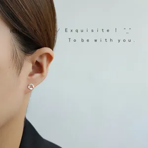 Nahaufnahme von silbernen Mini-Ohrringen mit geometrischem Design, eleganter Alltagsstil.