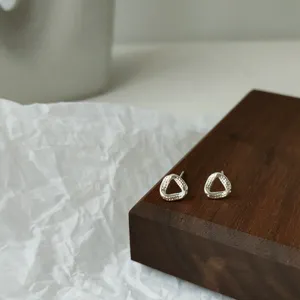 Nahaufnahme von minimalistischen sterlingvergoldeten geometrischen Dreieck Ohrringen Detail.