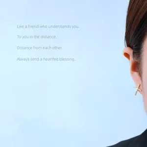 Detailaufnahme minimalistischer 14K vergoldeter Zirkonia Kreuz Ohrstecker für Damen.