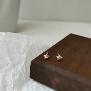 Detaillierte Nahaufnahme der zarten silbernen Stern Ohrstecker auf dem Holzdisplay.