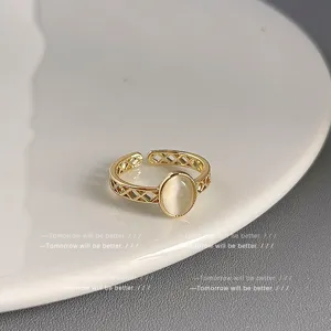 Detailaufnahme des verstellbaren goldenen offenen Rings mit ovalem weißem Stein, hohlem Design.