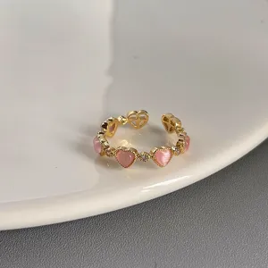 Vergoldeter Offener Ring mit rosa herzförmigen Steinen und funkelnden Zirkonia-Details.