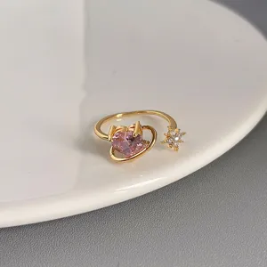 Nahaufnahme Detail eines goldenen offenen Rings mit rosa Herz Zirkon und einem funkelnden Stern.