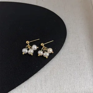 Detaillierte Nahaufnahme handgemachter Süßwasserperlen Ohrringe mit goldenen Stiften im Vintage-Stil.