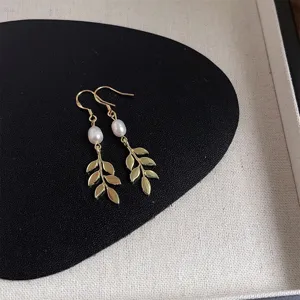 Detailaufnahme französischer Retro-Süßwasserperlen-Ohrringe mit Blättern und vergoldetem Design.