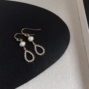 Detailansicht eleganter Süßwasserperlen und glitzernder Zirkon-Tropfenohrringe im Retro-Stil.