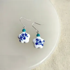 Handgemachte blau-weiße Porzellanblumen-Ohrringe mit Türkisperlen und silbernen Haken.