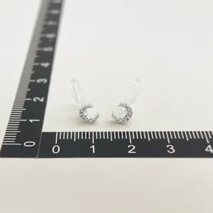 Close-up detail of clear clip-on earrings with sparkling micro-zirconia moon charms.