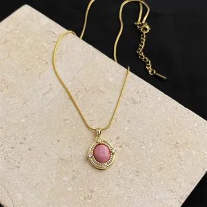 Close-up detail of 18k gold plated stainless steel necklace with pink natural stone pendant.