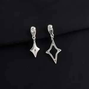 Close-up of asymmetric geometric star earrings, silver tone, detailed metal texture view.