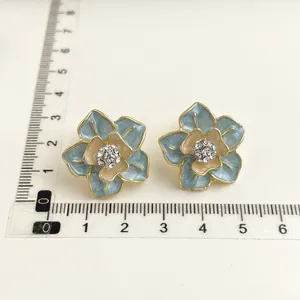 Orecchini a fiore in smalto con strass e bordo dorato, eleganti dettagli di gioielli da donna.