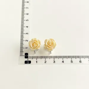 Detailed shot of sweet rose flower clip-on earrings with measurement ruler for size reference.