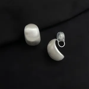 Silver matte curved clip-on earrings with invisible cushion, elegant minimalist design.