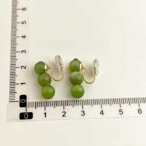 Orecchini a clip con tre perle di giada verde, dettagli dorati e morbidi cuscinetti.