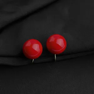 Detaillierte Nahaufnahme glänzender roter runder Ohrclips mit elegantem glatten Design.