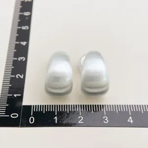 Close-up of minimalist brushed metal clip-on earrings, showing matte silver texture and details.