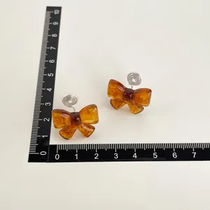 Bernsteinfarbene Harz Schleife Clip-Ohrringe mit Spulenpolstern, schicker Ohrschmuck Detail.