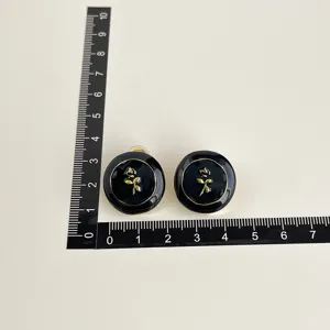 Elegante schwarze runde Ohrclips mit goldenem Rosendesign und bequemer Spulenpolsterung.
