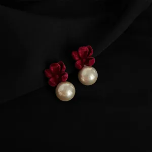Nahaufnahme eleganter Clip-Ohrringe mit dunklem Samt-Blumen-Detail und weißer Perle.