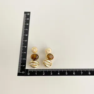 Detailansicht vergoldete Ohrclips ohne Ohrloch mit Tigerauge und funkelnden Zirkoniasteinen.