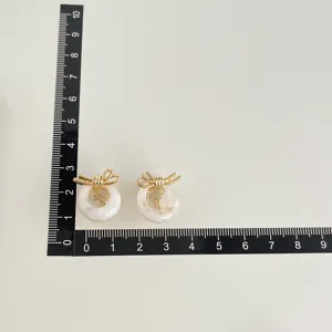Detailansicht von Ohrclips ohne Ohrloch mit goldener Schleife und weißem Ringdesign.