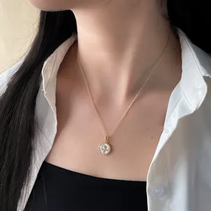 Vergoldete Schlüsselbeinkette mit rundem Perlmutt-Anhänger und filigranem Blumenmotiv für Damen.