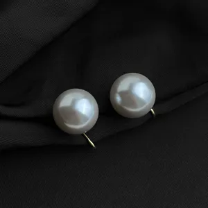 Nahaufnahme detailreicher eleganter Clip-Perlenohrringe mit goldfarbenem Metallglanz.