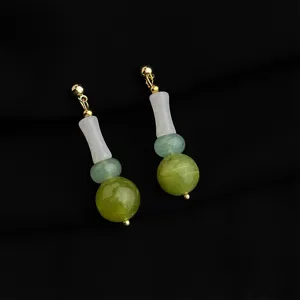 Orecchini pendenti in pietra verde e bianca con metallo dorato, dettaglio di gioielli.