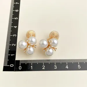 Perlen-Clip-Ohrringe im Cluster-Design mit funkelnden Strasssteinen und vergoldetem Detail.