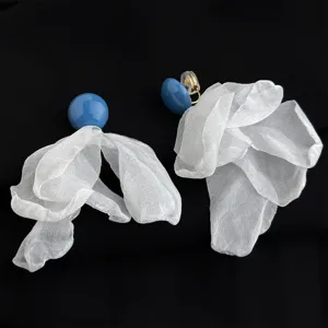 Primo piano dettagliato di eleganti orecchini a clip con perla blu e fiore in chiffon.