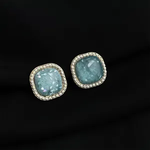 Primo piano dettagliato di eleganti orecchini quadrati con una raffinata trama in pietra blu.